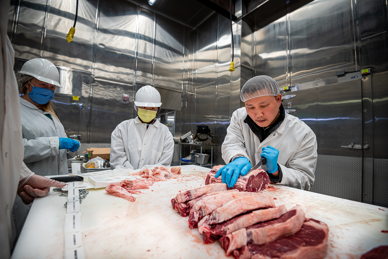 Dr. Thu Dinh, right, shows students how to cut beef at the MAFES Meat Science and Muscle Biology Laboratory. (Photo by David Ammon)
