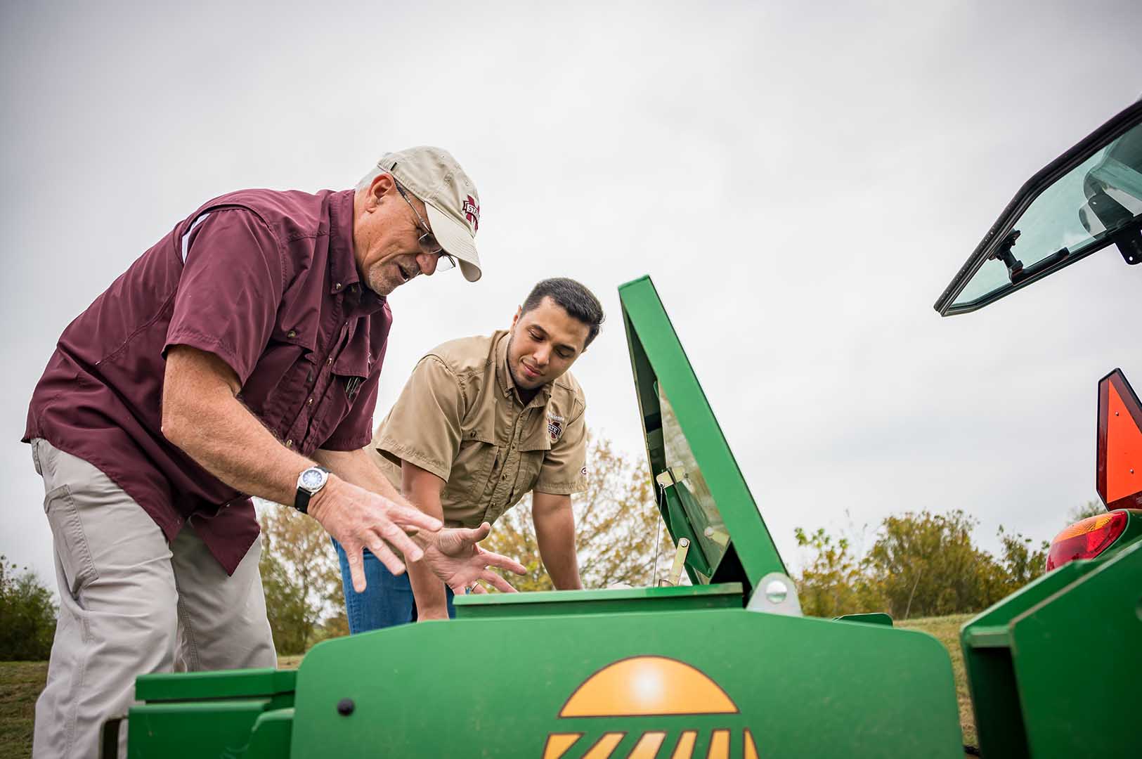 Cover crops are either drilled or broadcasted aerially. Dr. Jac Varco and graduate student Eduardo Garay check out the seed compartment of a drill. (Photo by David Ammon)