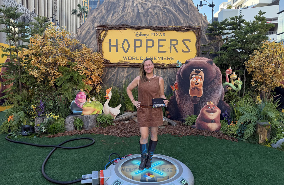 Holly Muraco on the set of the world premiere of Hoppers with animated animals on posters in the background