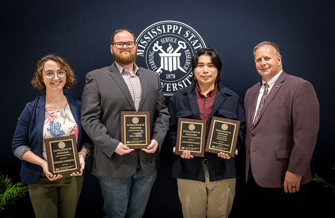 Faculty receive awards from Dean with a black background and the university seal
