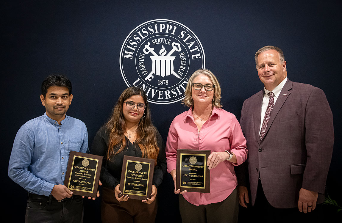 faculty holding plaques with the dean in front of a black background