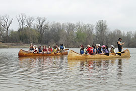 two groups of students in canoes on a river