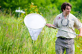 student in field with butterfly net