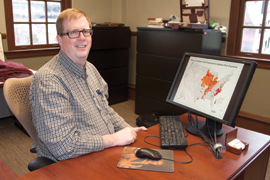 scientist with computer screen showing world map